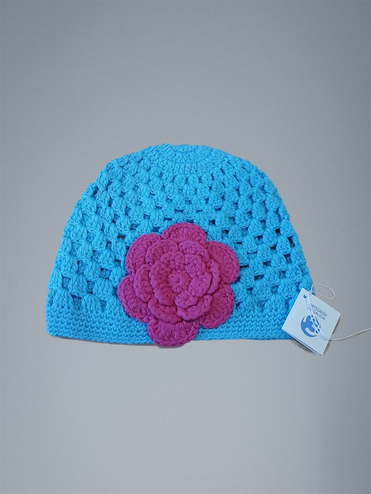 Gorro turquesa con flor fucsia hecho a mano a ganchillo. - Imagen 1